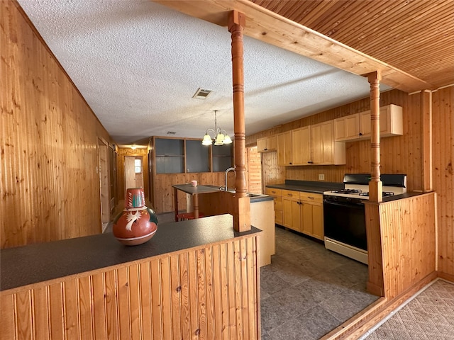 kitchen featuring white range with gas stovetop, wooden walls, and kitchen peninsula