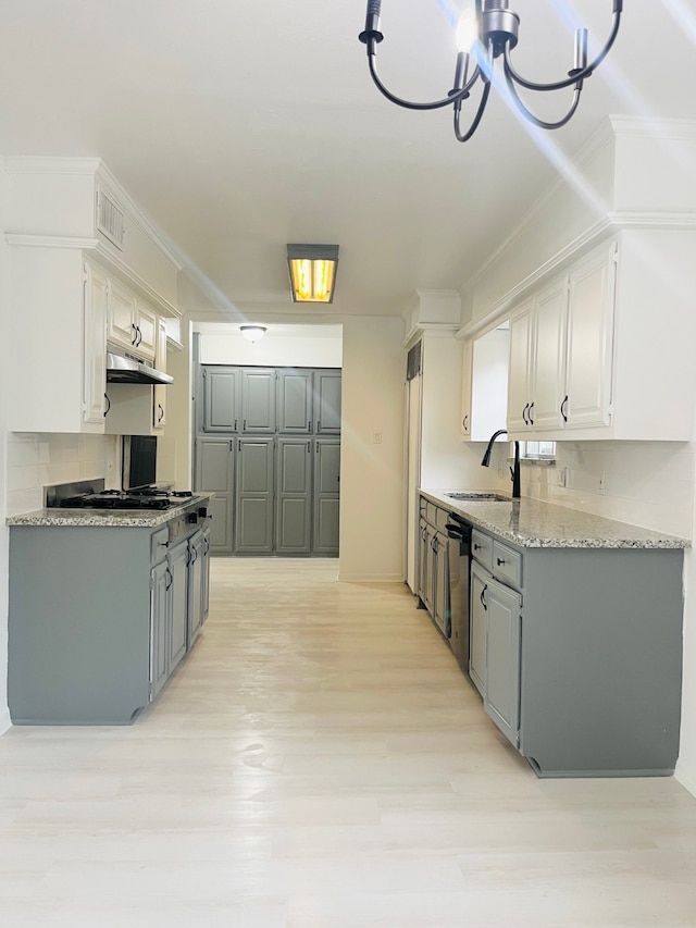 kitchen featuring tasteful backsplash, sink, white cabinetry, stainless steel dishwasher, and an inviting chandelier