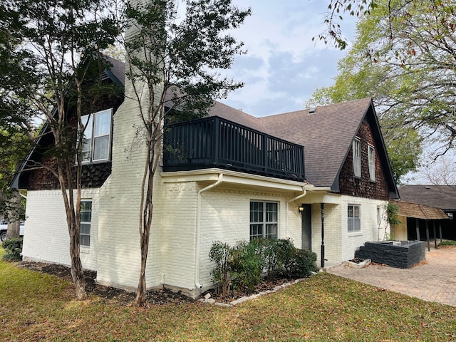 rear view of property featuring a balcony, a patio, and a lawn