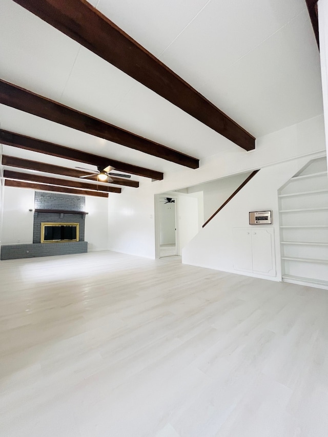 unfurnished living room with beam ceiling, a brick fireplace, light hardwood / wood-style floors, and ceiling fan