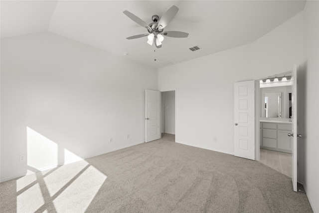 unfurnished bedroom featuring ceiling fan, ensuite bathroom, light colored carpet, and lofted ceiling