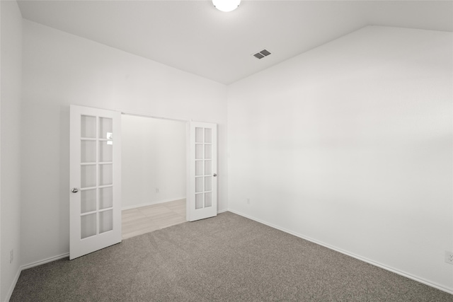 carpeted spare room with french doors and vaulted ceiling