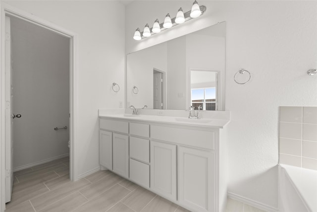 bathroom featuring vanity, a washtub, and toilet