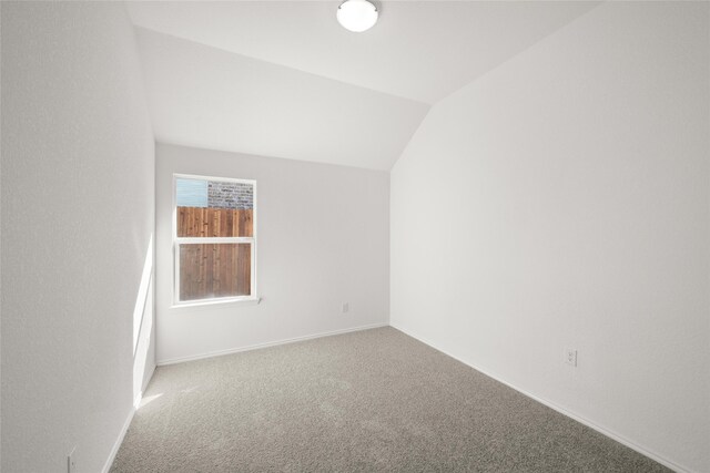 empty room featuring ceiling fan, light carpet, and vaulted ceiling