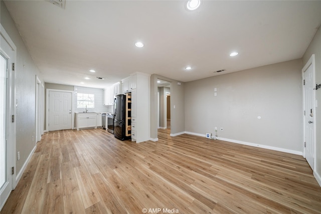 interior space with visible vents, baseboards, light wood-type flooring, a sink, and recessed lighting