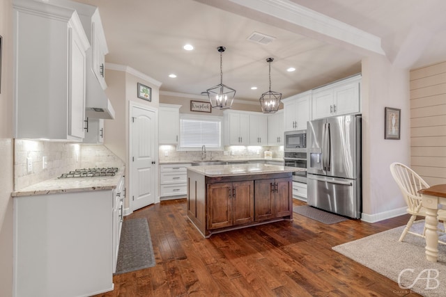 kitchen with sink, appliances with stainless steel finishes, white cabinetry, light stone countertops, and a kitchen island