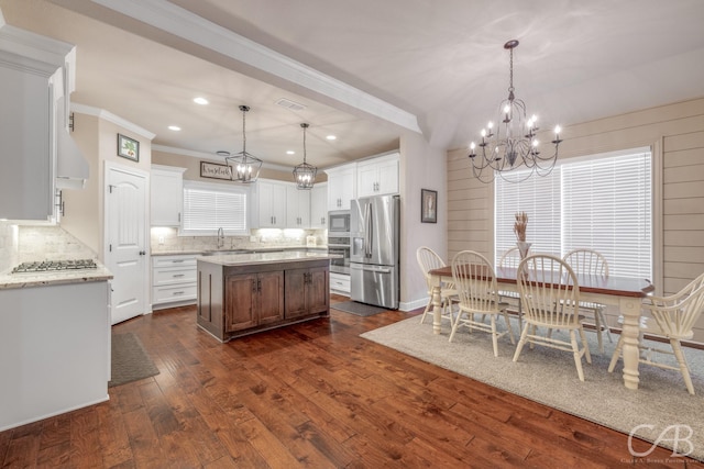 kitchen with stainless steel appliances, decorative light fixtures, a center island, and white cabinets