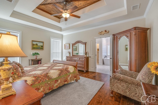 bedroom featuring dark hardwood / wood-style flooring, connected bathroom, crown molding, and a raised ceiling