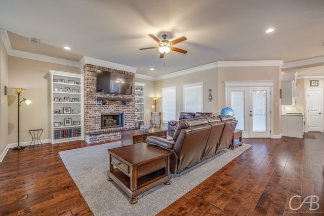 living room featuring crown molding, dark hardwood / wood-style floors, ceiling fan, built in features, and a fireplace