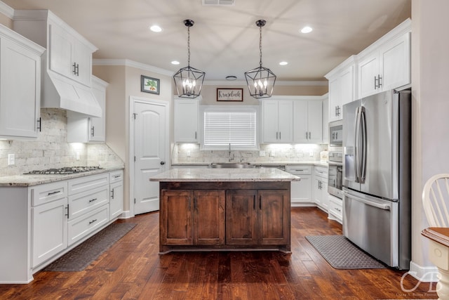 kitchen featuring sink, appliances with stainless steel finishes, hanging light fixtures, a center island, and white cabinets