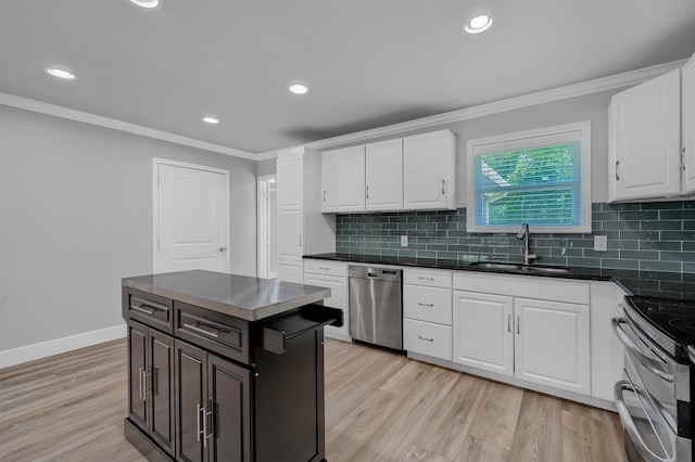 kitchen featuring white cabinetry, stainless steel appliances, sink, ornamental molding, and light hardwood / wood-style flooring