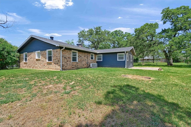 back of property featuring central air condition unit and a lawn