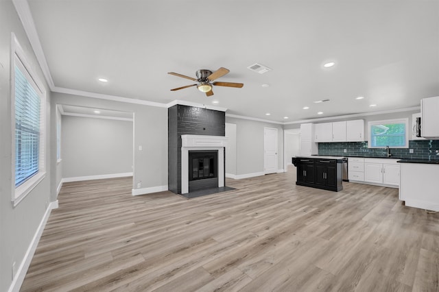 kitchen with a fireplace, tasteful backsplash, sink, light hardwood / wood-style flooring, and ornamental molding