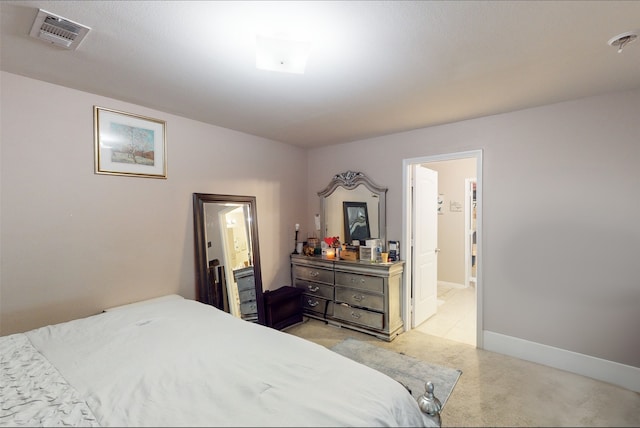 bedroom with connected bathroom and light carpet