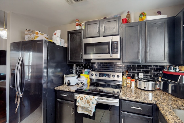 kitchen featuring light stone countertops, tile patterned floors, decorative backsplash, and appliances with stainless steel finishes