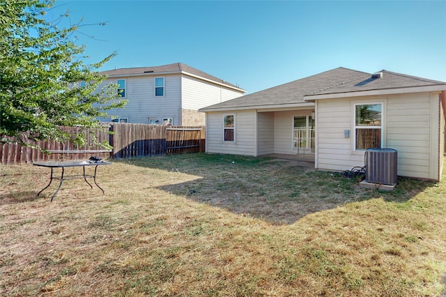 rear view of property with a yard and central air condition unit