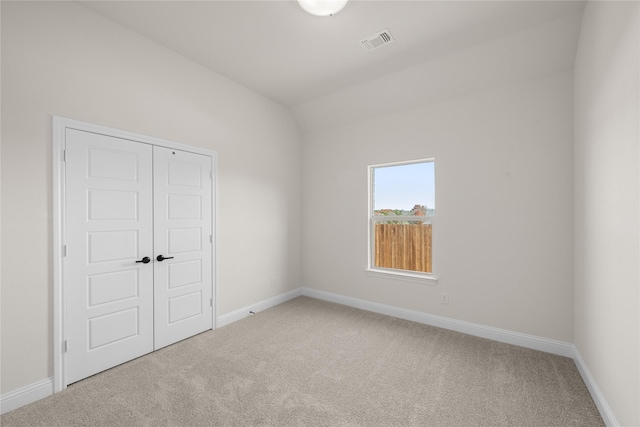 unfurnished room featuring vaulted ceiling and carpet floors