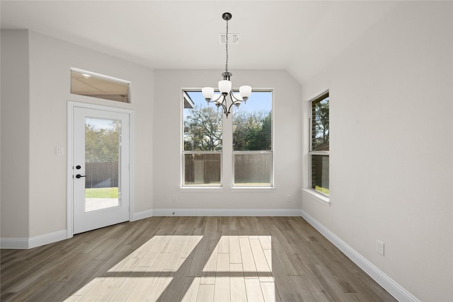 unfurnished dining area featuring wood-type flooring and an inviting chandelier