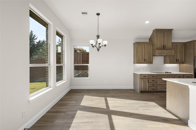 kitchen featuring an inviting chandelier, hanging light fixtures, black electric cooktop, decorative backsplash, and light wood-type flooring