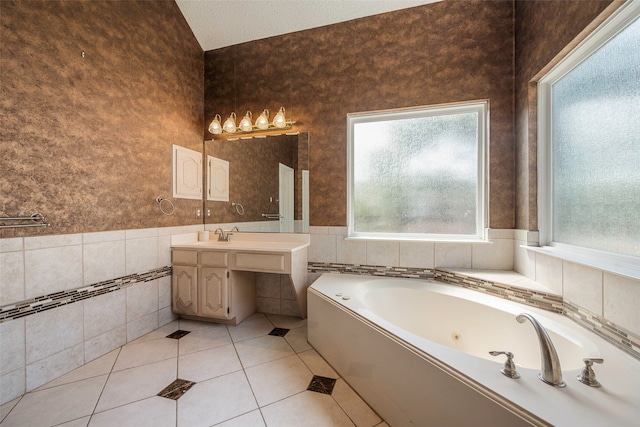 bathroom featuring a tub to relax in, tile patterned flooring, vanity, tile walls, and a textured ceiling