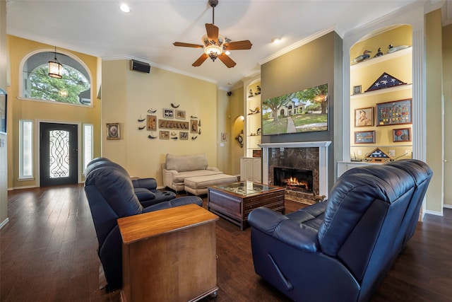 living room with dark hardwood / wood-style floors, a high end fireplace, crown molding, built in shelves, and ceiling fan