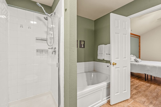 bathroom with wood-type flooring and shower with separate bathtub