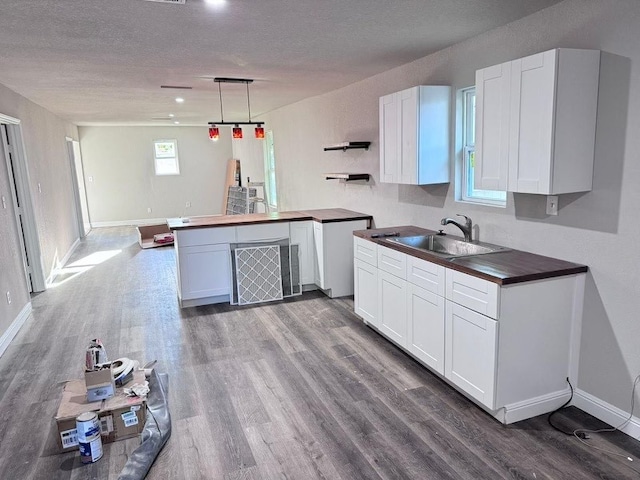 kitchen featuring white cabinetry, sink, wood-type flooring, and decorative light fixtures