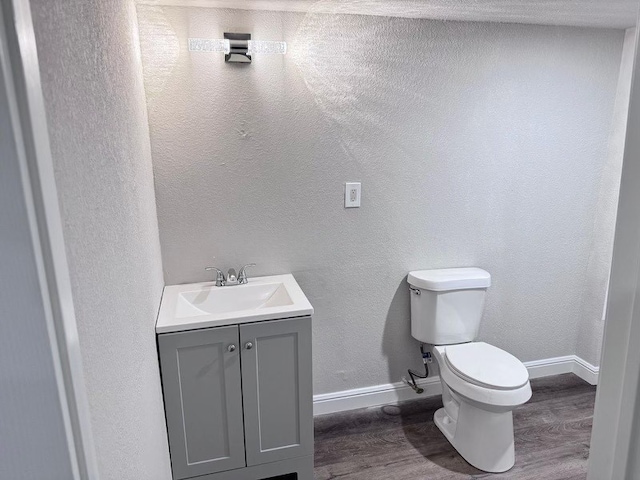 bathroom with vanity, toilet, and hardwood / wood-style floors