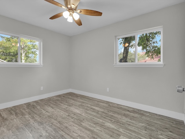 empty room with hardwood / wood-style floors, ceiling fan, and a wealth of natural light