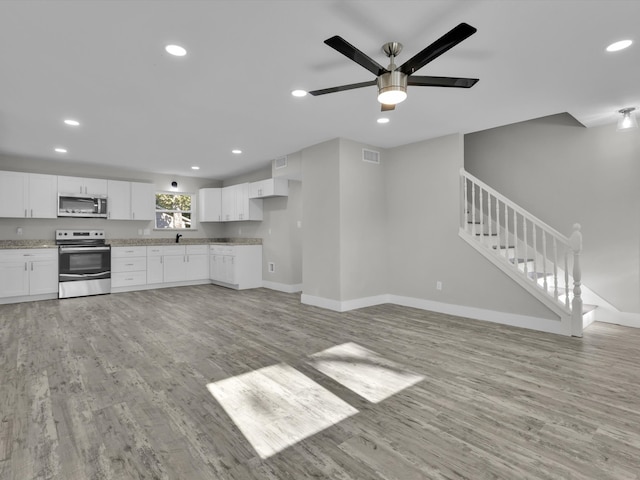 kitchen with light stone counters, ceiling fan, white cabinetry, light hardwood / wood-style floors, and stainless steel appliances