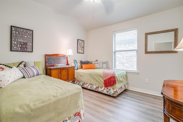 bedroom featuring ceiling fan, light hardwood / wood-style flooring, and lofted ceiling