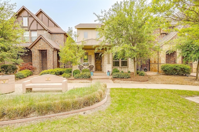 tudor home with a porch and a front yard