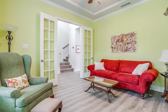 living room featuring french doors, light hardwood / wood-style floors, and crown molding