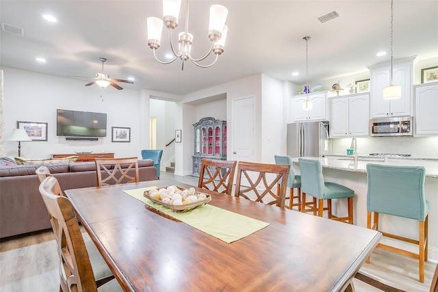 dining room featuring light hardwood / wood-style floors and ceiling fan with notable chandelier