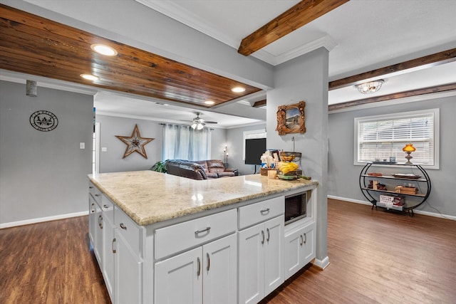 kitchen with dark wood-type flooring, ceiling fan, light stone countertops, built in microwave, and white cabinetry