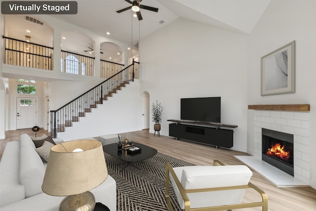 living room featuring high vaulted ceiling, ceiling fan, and light wood-type flooring