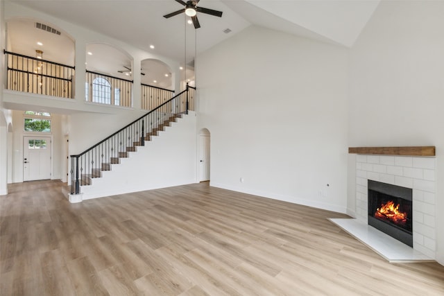 unfurnished living room with ceiling fan, light wood-type flooring, and high vaulted ceiling