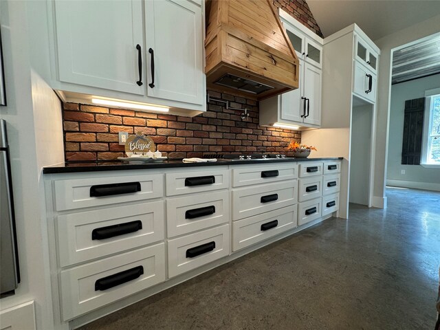 kitchen with custom range hood, tasteful backsplash, and white cabinets