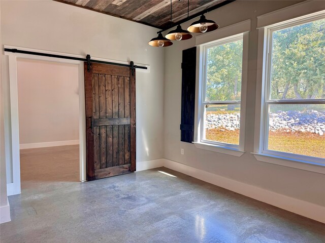 empty room with concrete floors, wooden ceiling, and a barn door