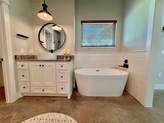 bathroom with vanity, a tub, and concrete flooring