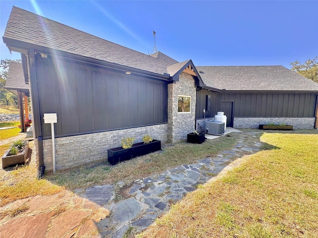 166 Oak Ridge Loop, Whitney, TX 76692 - view of side of home featuring stone siding, a shingled roof, central AC, and a yard