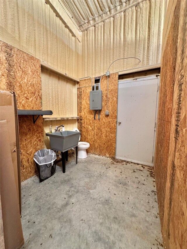 bathroom with toilet, electric panel, sink, and concrete flooring