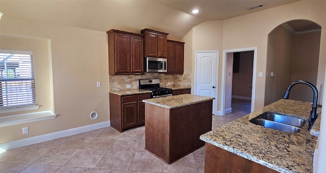 kitchen featuring appliances with stainless steel finishes, backsplash, sink, a center island with sink, and lofted ceiling