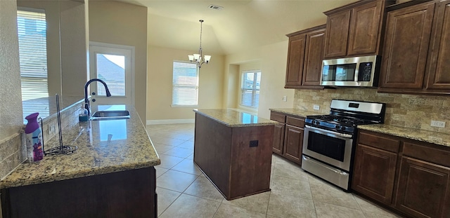 kitchen featuring decorative backsplash, stainless steel appliances, sink, a center island with sink, and an inviting chandelier