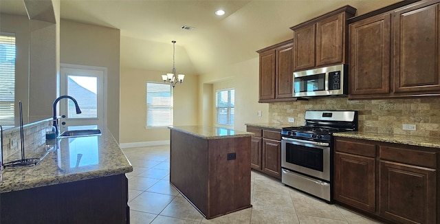 kitchen with sink, vaulted ceiling, a kitchen island, stainless steel appliances, and a chandelier