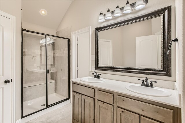 bathroom with a shower with door, vanity, vaulted ceiling, and tile patterned flooring