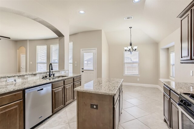 kitchen featuring lofted ceiling, sink, dark brown cabinets, appliances with stainless steel finishes, and a kitchen island