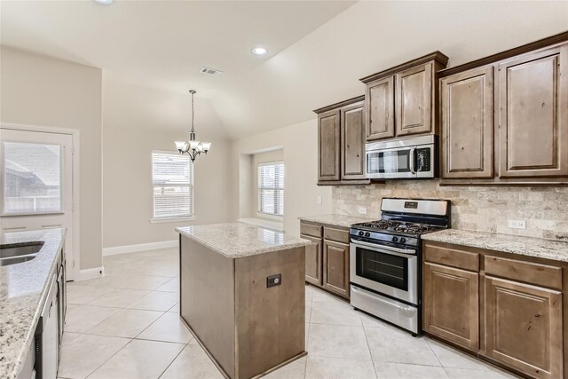 kitchen with light stone countertops, stainless steel appliances, tasteful backsplash, and lofted ceiling