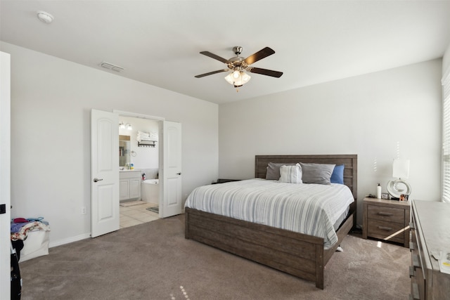 carpeted bedroom with ensuite bath and ceiling fan