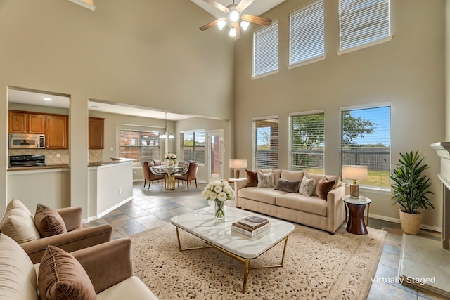 living area with ceiling fan, a high ceiling, and baseboards